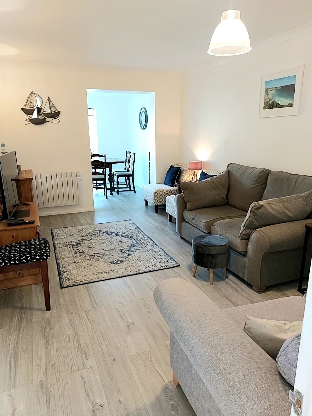 Una sala de estar con sofá, una mesa de centro, un tapete y un comedor con sillas y una mesa.