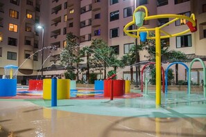 Kids can play and splash in the hotel's outdoor water play area, surrounded by lush greenery and modern play structures.