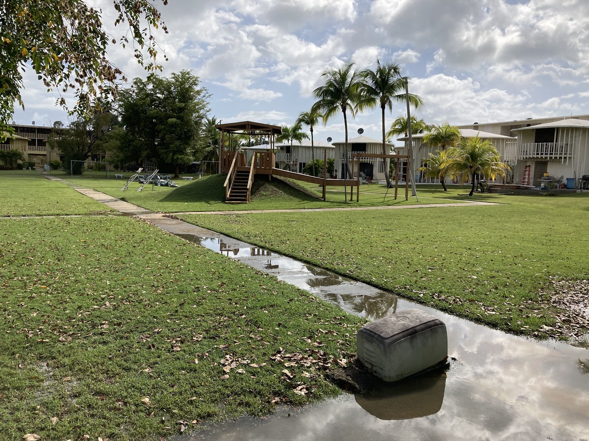 A grassy area with a small water feature, a wooden staircase, and a covered seating area.