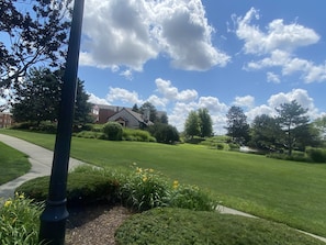 A well-maintained lawn with a pathway, a building with a brick facade, and a flag. - Lovely 2 bedrooms apartment 10min from O'HARE CHICAGO (Rosemont)