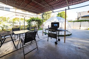 Relax in the covered patio area with a table, chairs, grill, and greenhouse.