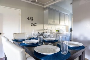 Enjoy meals in this stylish dining area with a set table and modern kitchen backdrop.