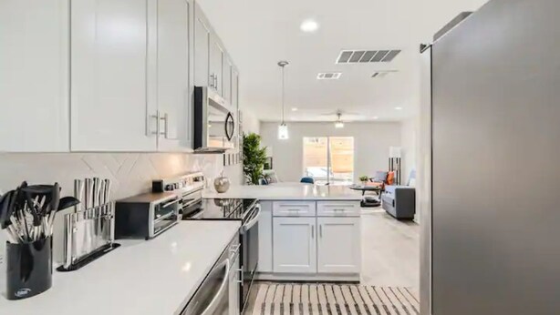 A modern kitchen with white cabinets, a built-in oven, and a large island.