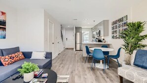A modern living room with a sofa, coffee table, and a dining area with chairs.
