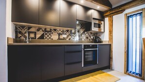 A modern kitchen with dark cabinets, a patterned backsplash, and built-in appliances.