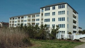 Un edificio residencial de varios pisos con balcones, techo plano y fachada blanca.