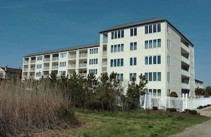 Um edifício residencial de vários andares, com varandas, um telhado plano e fachada branca.