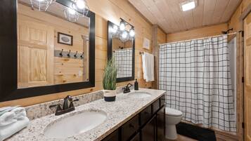 Une salle de bain avec des murs en bois, deux lavabos, des toilettes et un rideau de douche.