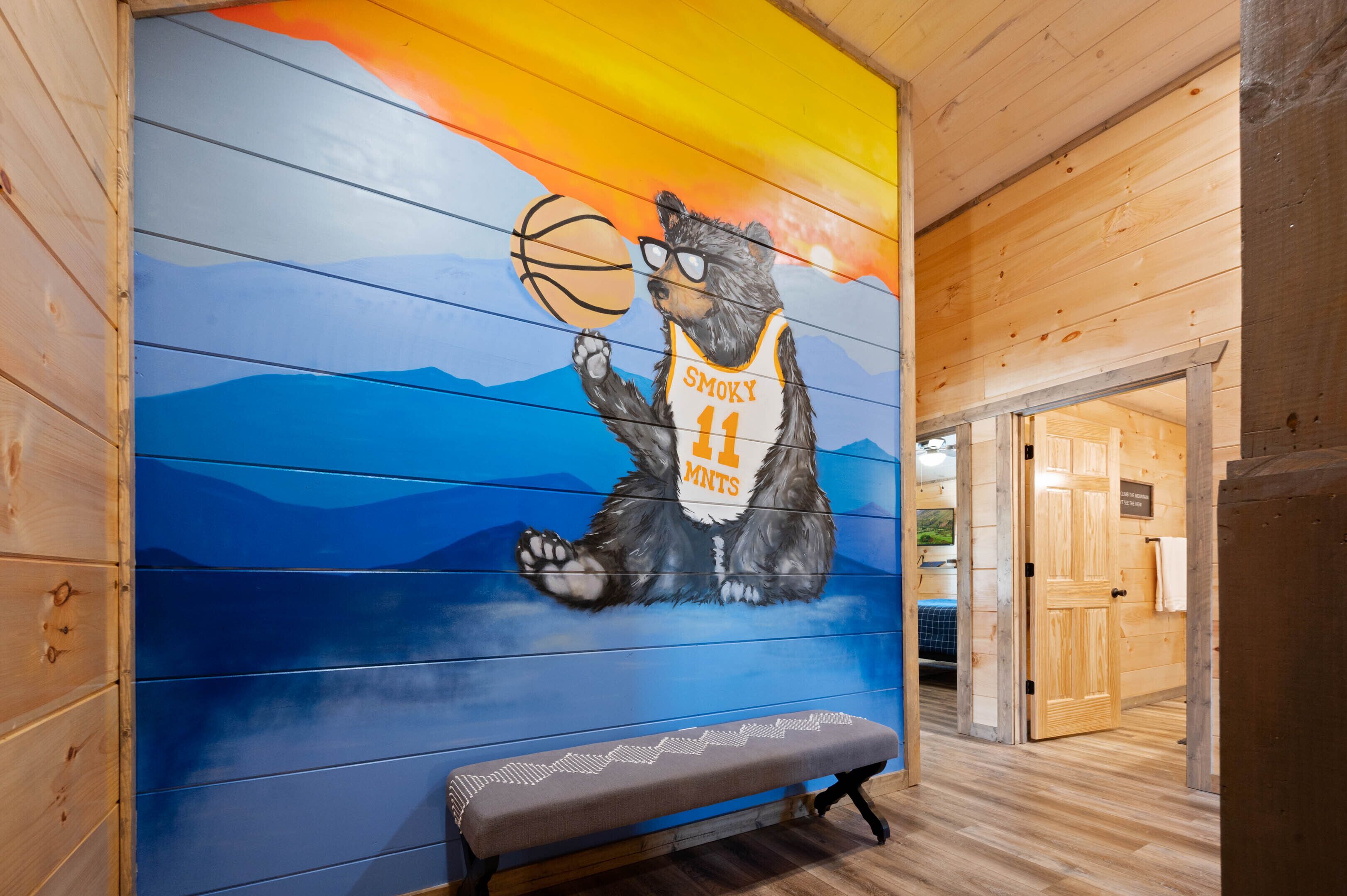 A mural of a bear holding a basketball with the text "SMOKY MAMPS 11" on a wall.