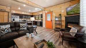 Un intérieur de chalet chaleureux comprenant un salon, une cuisine et une cheminée.