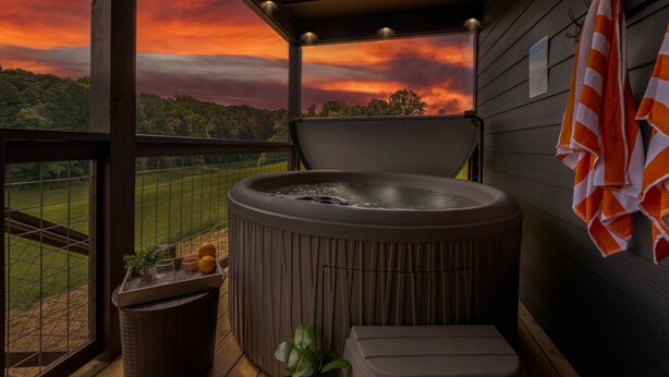 Un bain à remous sur un balcon, avec vue sur un champ et sur le coucher du soleil.
