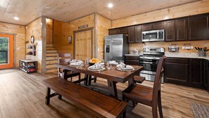 L’intérieur d’un chalet en bois comprend une table à manger pour quatre personnes, un réfrigérateur, un four à micro-ondes et une cuisinière.