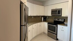 Uma cozinha moderna com armários brancos, eletrodomésticos de aço inoxidável e bancada de granito.