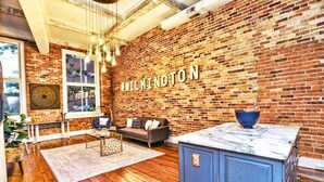 Un salon moderne avec un mur en briques, un canapé, une table basse et un coin cuisine doté d’un plan de travail en marbre.