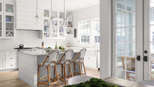 A modern kitchen with white cabinetry, a central island with bar stools, pendant lighting, and a view through a glass door. -  #1 VRBO in Austin HEATED POOL, central to 6th and Rainey (Austin)