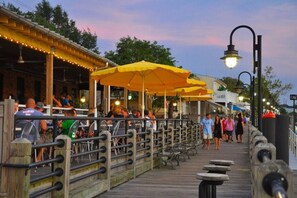A wooden boardwalk with outdoor seating and yellow umbrellas, surrounded by buildings and trees. - LUXURY LOFT on MARKET!!! (Wilmington)