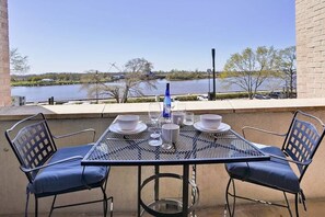 An outdoor patio with a table set for two, overlooking a body of water.