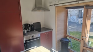 Eine kleine Küche mit Herd, Backofen und Kaffeemaschine.