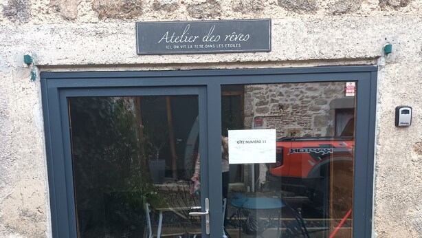 Ein Gebäudeeingang mit einem Schild, auf dem „Atelier des rênes“ steht, und einer Tür mit dem Schild „Gîte numéro 11“.