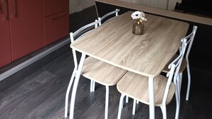 Eine kleine Küche mit Esstisch, weißen Stühlen und einem kleinen Fenster.