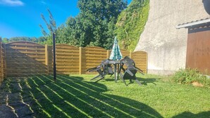 Ein Garten mit Holzzaun, Terrassentisch und -stühlen sowie einem kleinen Gartenbereich.