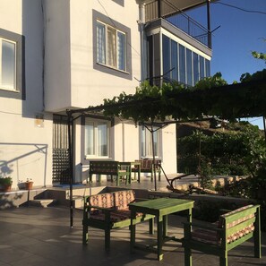 Rakennuksessa on parveke, ulkotila istumista varten sekä viiniköynnöksillä koristeltu pergola.