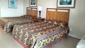 A hotel room with two beds, each with patterned bedding, a nightstand with a lamp, and framed artwork on the walls. - Pharr Executive Inn (Pharr)