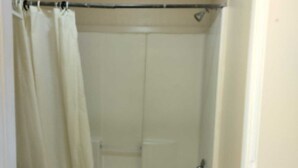 A small bathroom with a toilet, a bathtub, and a shower curtain. - Pharr Executive Inn (Pharr)