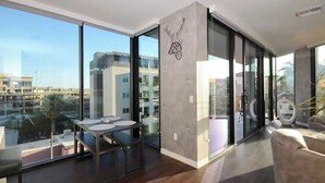 A modern interior with a dining area, large windows, and a view of buildings. - Luxury High Rise Flat - Free Underground Parking (Tucson)