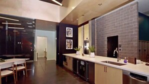 A modern kitchen with a brick accent wall, stainless steel appliances, and a minimalist design. - Luxury High Rise Flat - Free Underground Parking (Tucson)