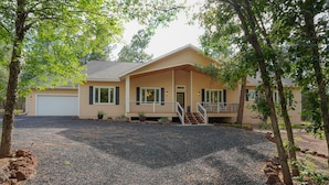 A two-story house with a covered porch, a front garage, and a gravel driveway. - AMAZING 4300 SQ FEET RETREAT ON  4.5 ACRES WITH AC!! SLEEPS 16 PETS WELCOME! (Pinetop-Lakeside)
