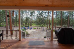 A wooden deck with a stone patio, outdoor seating, and a view of a forested area. - AMAZING 4300 SQ FEET RETREAT ON  4.5 ACRES WITH AC!! SLEEPS 16 PETS WELCOME! (Pinetop-Lakeside)