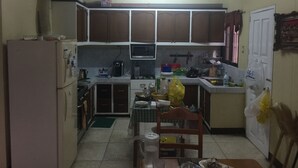 A compact kitchen with basic appliances, a dining area with a chair, and a small table. - Gated community (Davao city)