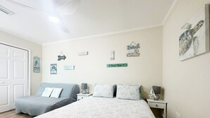 A bedroom with two beds, a ceiling fan, and wall decorations including a beach theme. - Private Suite · Patio · BBQ · GYM · Beach: 5 Miles (Largo)