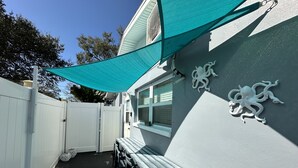 A patio area with a white fence, a bench, and a decorative octopus sculpture on the wall. - Private Suite · Patio · BBQ · GYM · Beach: 5 Miles (Largo)