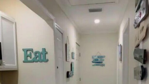 A narrow hallway with a kitchen area on the left, a small table with a blue chair, and a trash bin. - Private Suite · Patio · BBQ · GYM · Beach: 5 Miles (Largo)