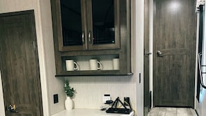 Een kleine keuken met donker houten kastjes, een aanrecht en een inbouwoven.