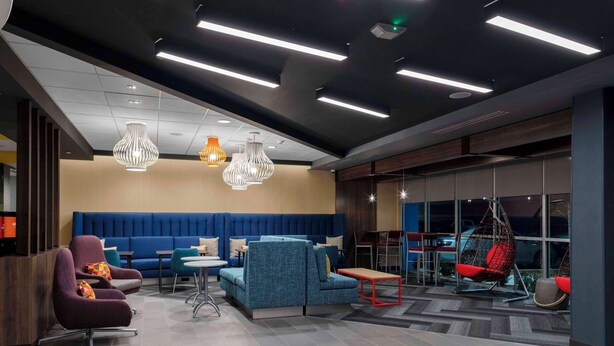 A modern lobby with seating areas, a blue sofa, and hanging lights. - Tru By Hilton Manteca, Ca (Manteca)