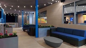 A modern lobby with a blue sofa, a round coffee table, and a reception desk. - Tru By Hilton Manteca, Ca (Manteca)