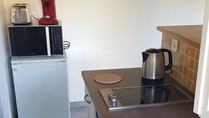 Eine kleine Küche mit Kühlschrank, Mikrowelle, Toaster und Kaffeemaschine.