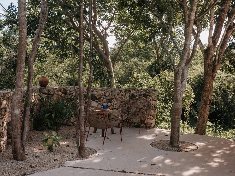 Una zona de estar al aire libre con muros de piedra y árboles.