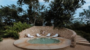 A hot tub surrounded by stone walls and white lounge chairs. - Galopina (Seyé)