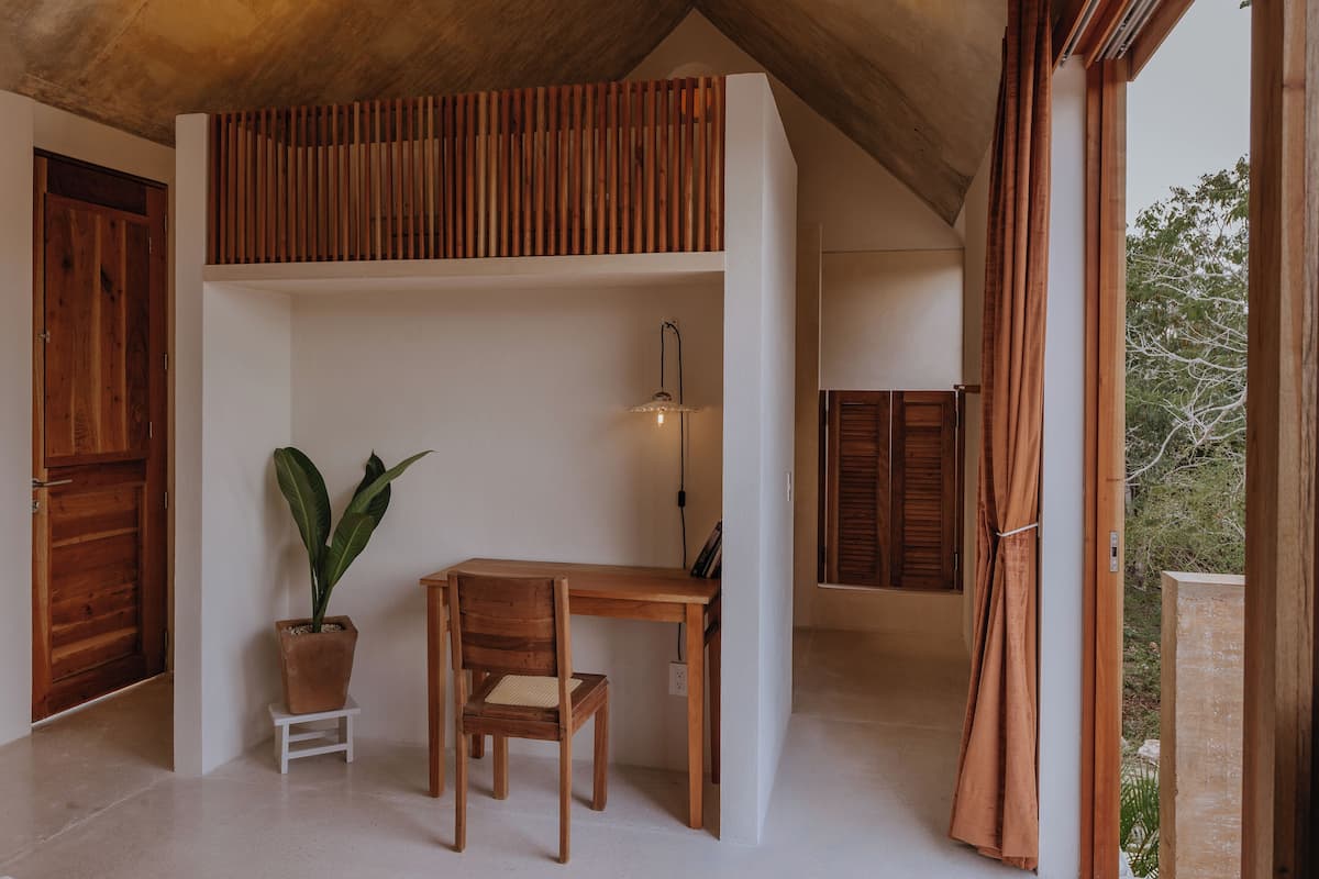 Una habitación con escritorio de madera, silla y planta en maceta.