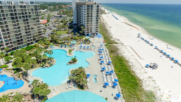 A resort with a large pool area, beach, and high-rise buildings.