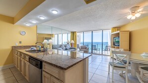 A spacious living area with a large island, a dining table, and a view of the ocean.