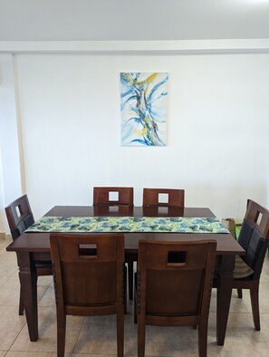A dining area with a rectangular table, four wooden chairs, and a colorful table runner. - Beachfront Bliss (Nueva Gorgona)