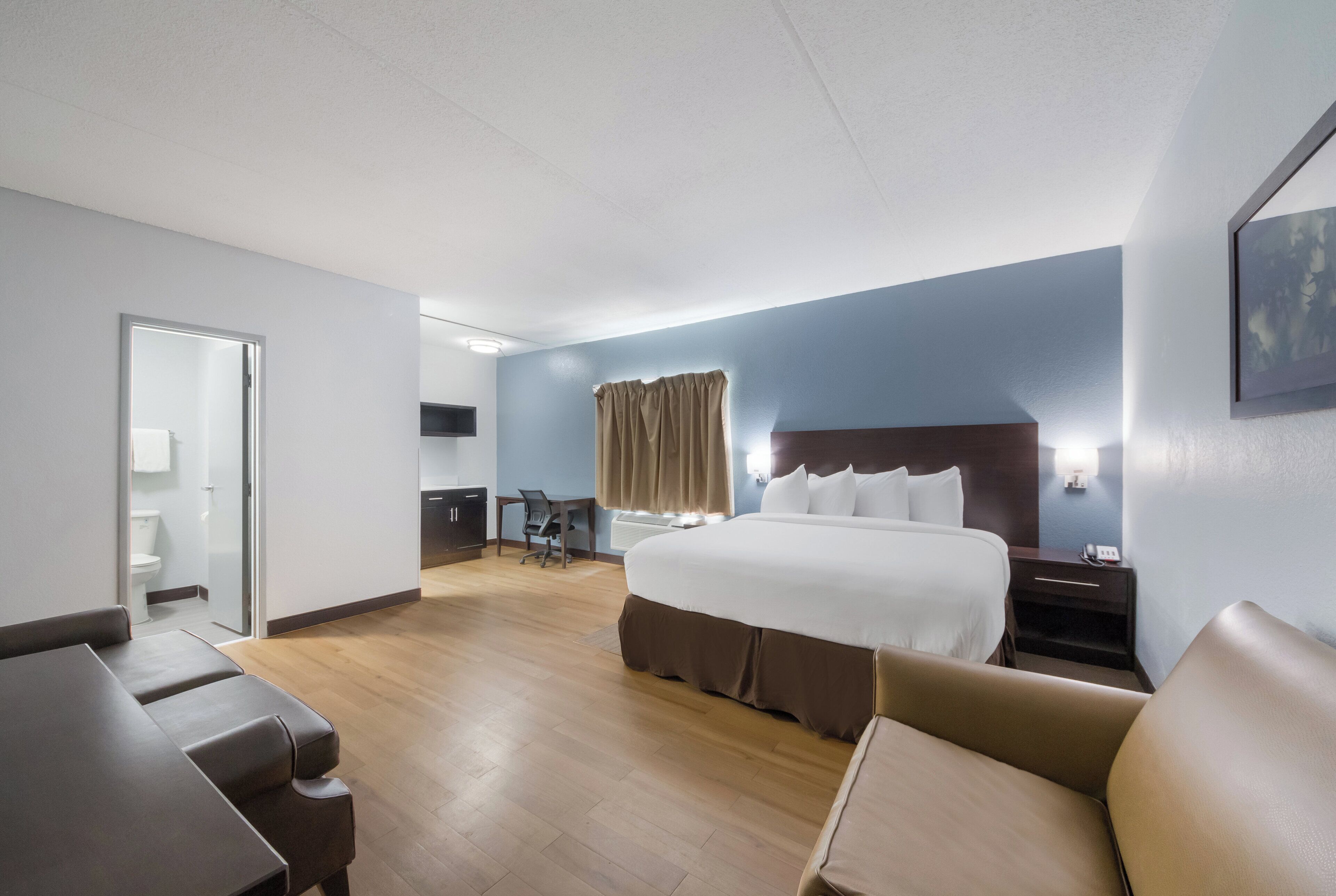 A hotel room with a large bed, a desk, a chair, and a bathroom.