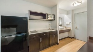 Una cocina compacta con refrigerador, microondas, lavaplatos y armarios.