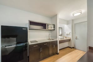 Una cocina compacta con refrigerador, microondas, lavaplatos y armarios.
