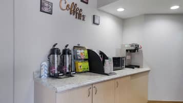 Eine Kaffeestation mit Kaffeemaschine, Wasserkochern und einer Kaffeetassenhalterung.